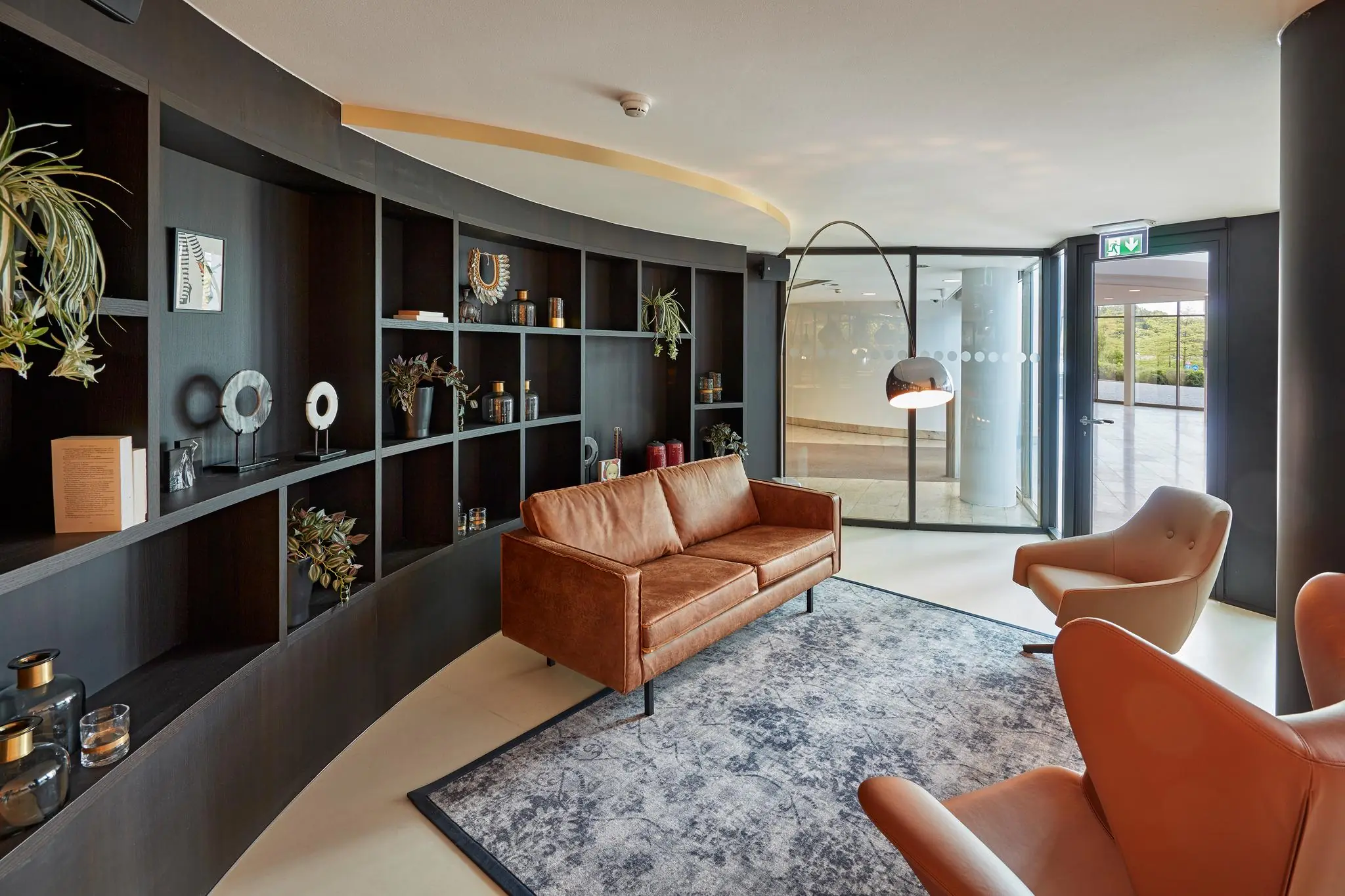 Moderne wachtruimte aan de Fascinatio Boulevard met leren meubels, open wandkast en grote glazen ingang.